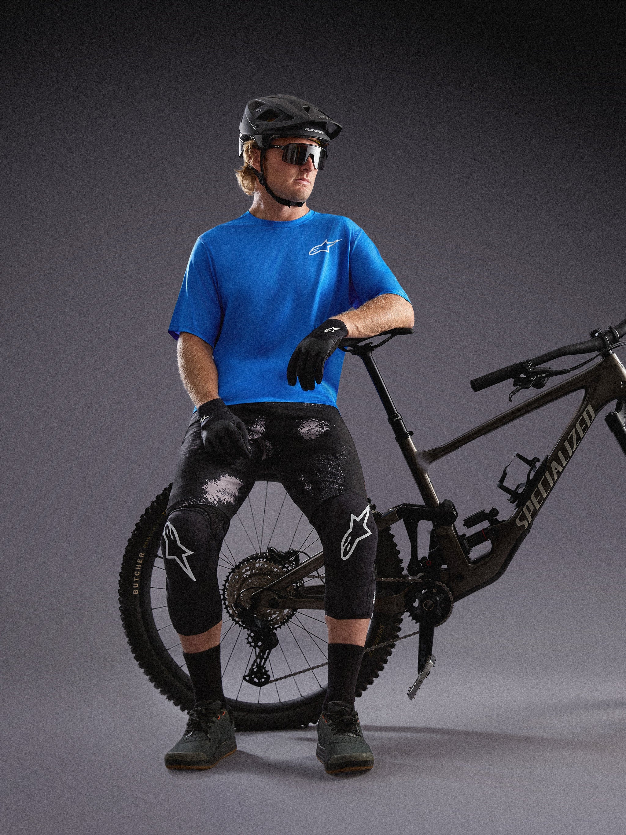 Alpinestars A-Dura Air SS jersey i blå og Black Camo shorts, vist med mountainbike og beskyttelsesudstyr i et studie.