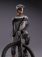 Alpinestars A-Dura Race langærmet trøje i grå på en MTB-rytter med sorte detaljer og professionelt cykeludstyr.