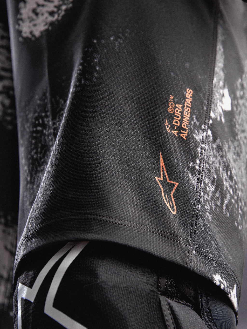 A-Dura Ride Shorts i sort camouflage med orange Alpinestars-logo på holdbart 4-vejs strækstof til MTB.