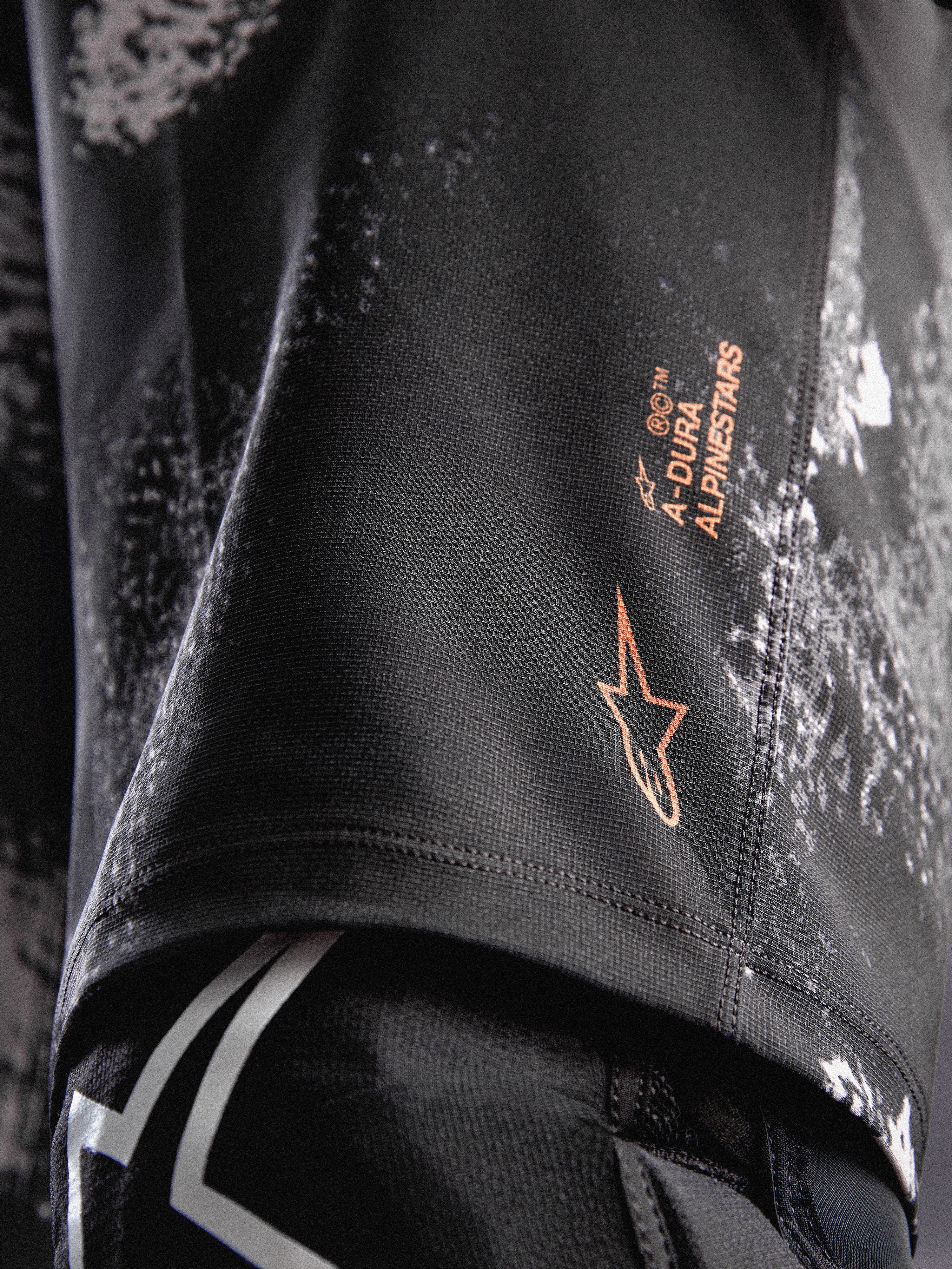 A-Dura Ride Shorts i sort camouflage med orange Alpinestars-logo på holdbart 4-vejs strækstof til MTB.