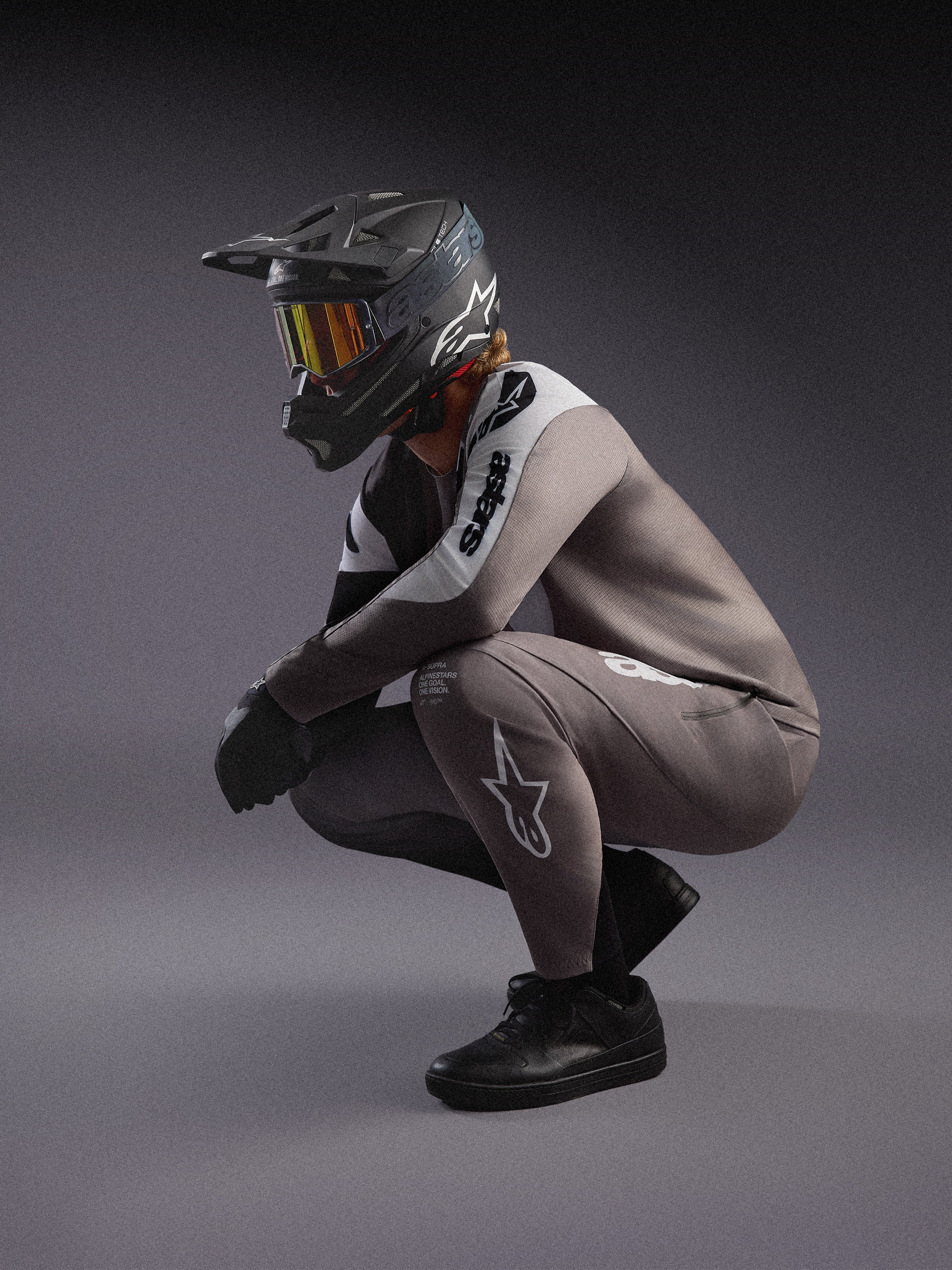 Falmet grå A-Supra Elite MTB-trøje og bukser, kombineret med en sort full-face hjelm og goggles til racing.