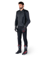Alpinestars Missile V3 læderjakke, sort, båret af en rytter med sorte bukser og sort-røde racinghandsker og støvler, med perforerede læderpaneler og stilfuld monokromatisk branding, professionel racing sport-æstetik