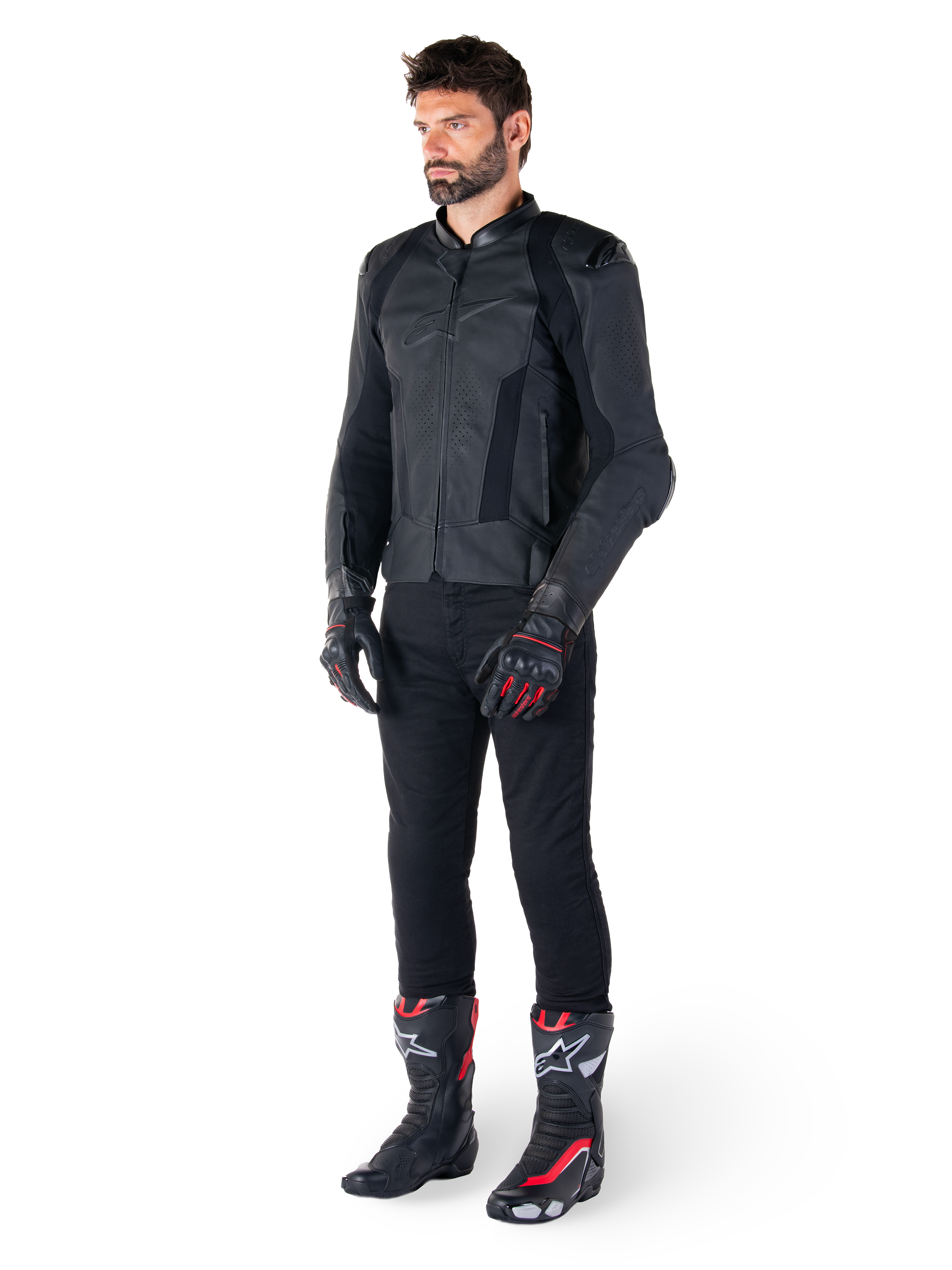 Alpinestars Missile V3 læderjakke, sort, båret af en rytter med sorte bukser og sort-røde racinghandsker og støvler, med perforerede læderpaneler og stilfuld monokromatisk branding, professionel racing sport-æstetik