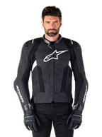 Alpinestars Missile V3 læderjakke, sort med hvide logoer, båret af en model med sorte kørehandsker, premium læder motorcykel racingjakke med perforerede ventilationspaneler og performance-køreegenskaber