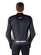 Bagsiden af Alpinestars Missile V3 læderjakken i sort og hvid, med Alpinestars stjernelogo på den øverste del af ryggen og branding på lænden, hvide lodrette striber og udvendige albue-sliders, premium racing sportslæderjakke.