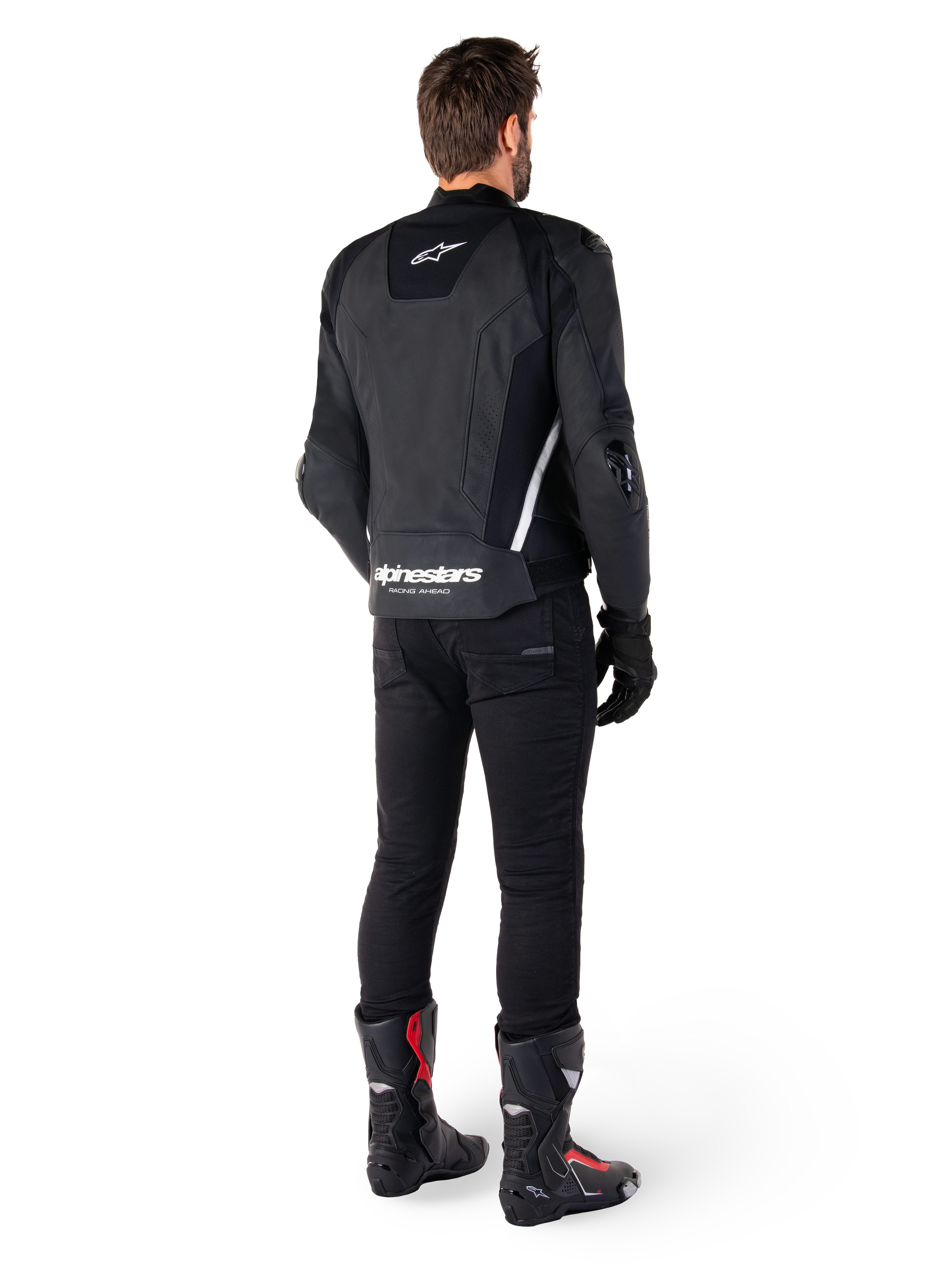 Alpinestars Missile V3 læderjakke, sort og hvid, set bagfra på køreren, med tydelig hvid Alpinestars-branding på den nederste del af ryggen og et lille logo øverst, båret med sorte bukser og racingstøvler, premium læderkonstruktion til motorcykelracing