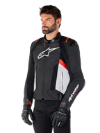 Alpinestars Missile V3 læderjakke, sort, hvid og rød fluo, racing sport motorcykeljakke båret af en model med sorte handsker og bukser, med perforerede læderpaneler og markant Alpinestars-branding