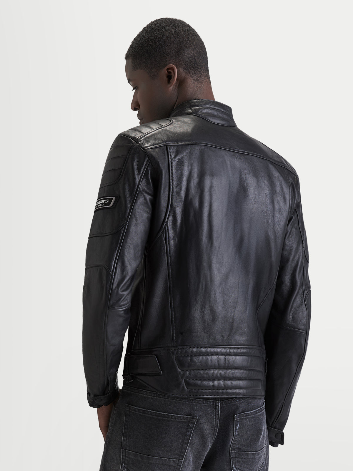 Alpinestars Revern Læderjakke, herre-motorcykeljakke i sort, set bagfra på en model, der viser slidt fuldnarvet læderkonstruktion, klassisk biker-krave og heritage-stil brandingdetaljer