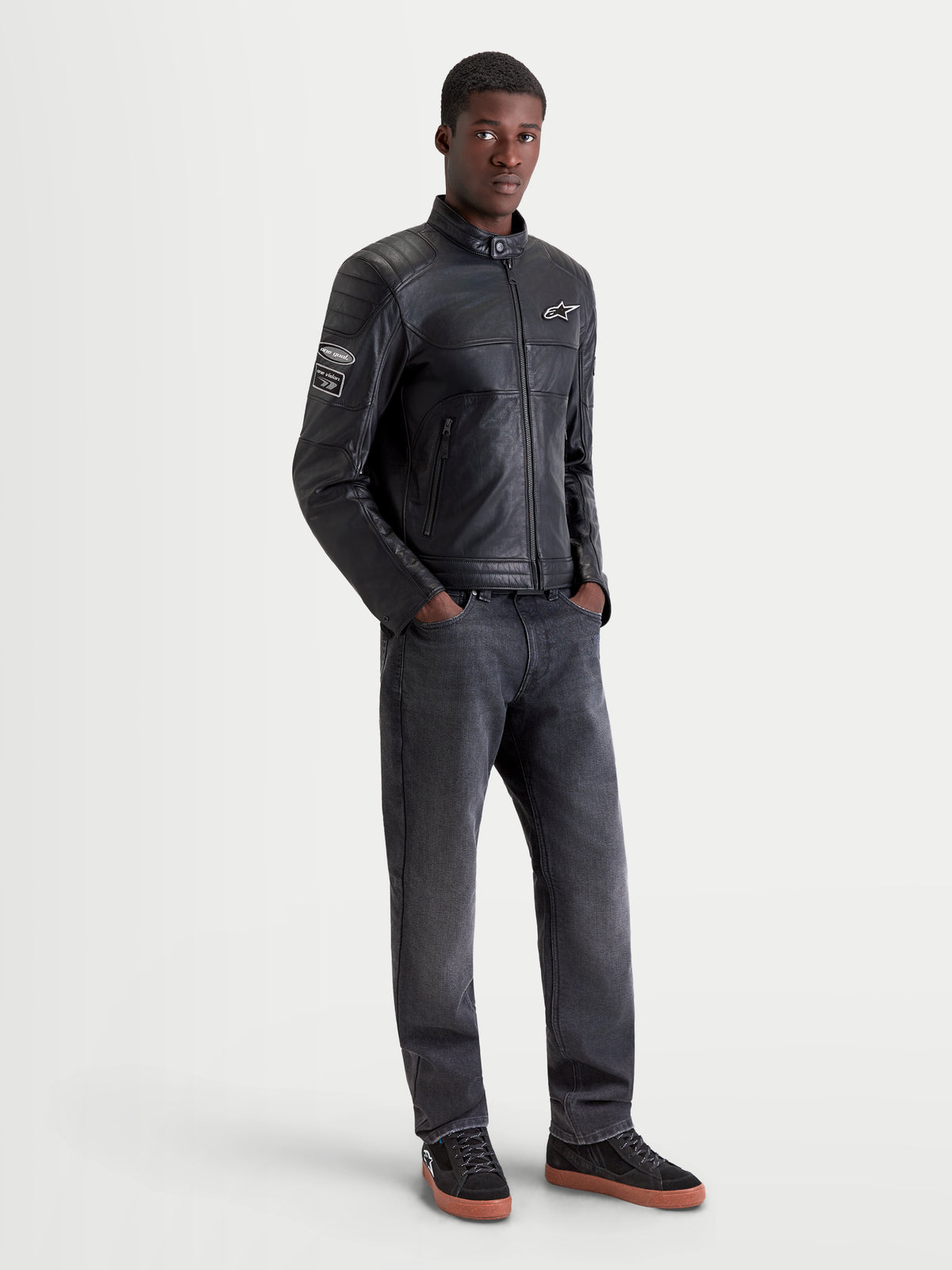 Alpinestars Revern Leather Jacket, men's urban motorcycle leather jacket in black, front view on a model wearing dark jeans and riding shoes, featuring heritage styling and distressed full-grain bovine leather construction.