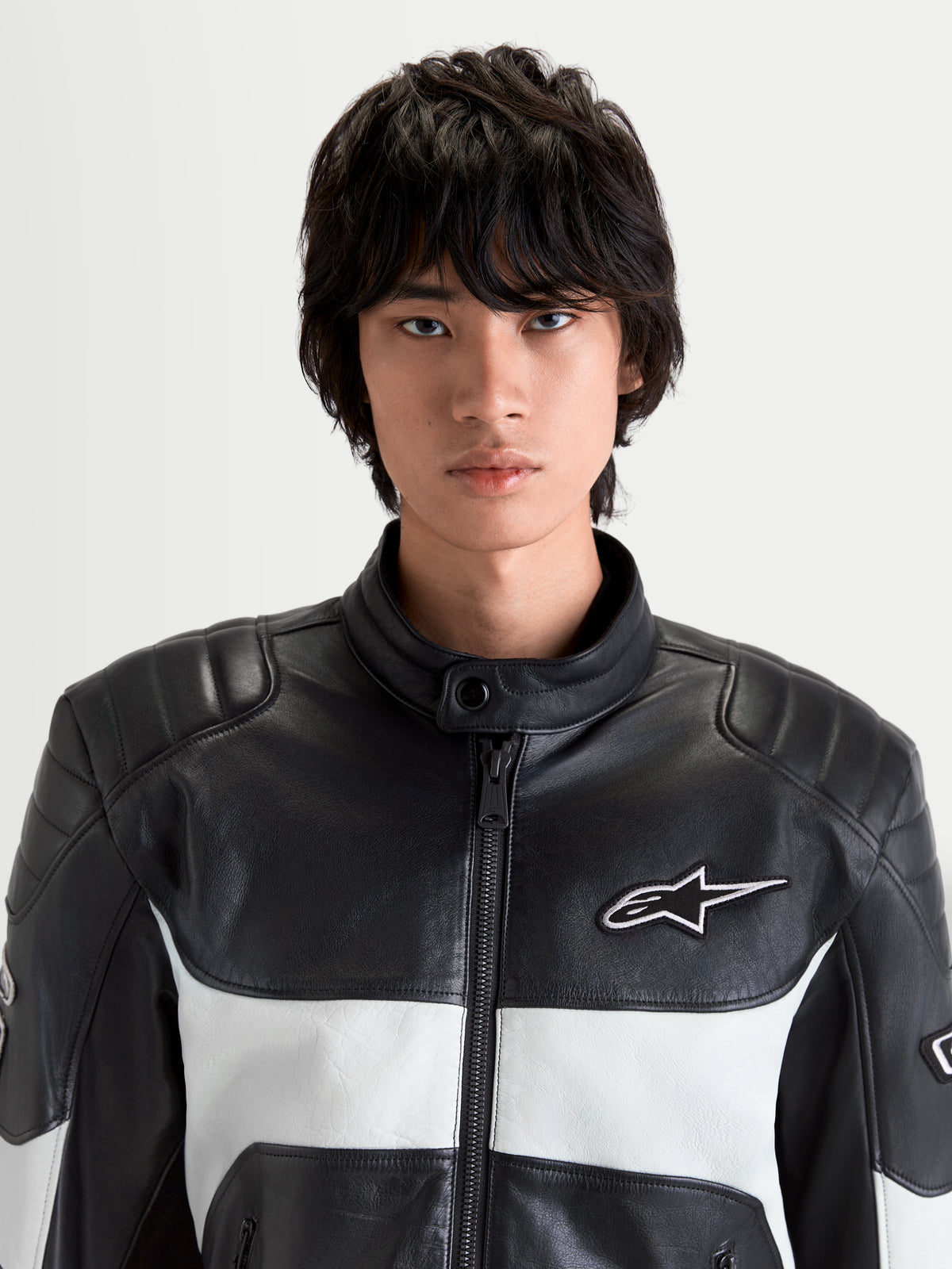 Alpinestars Revern Læderjakke, herre-motorcykeljakke i sort og metalgrå, tæt på forfra af model der viser fuldnarvslæderkonstruktion, biker-krage og hvidt Alpinestars-logo