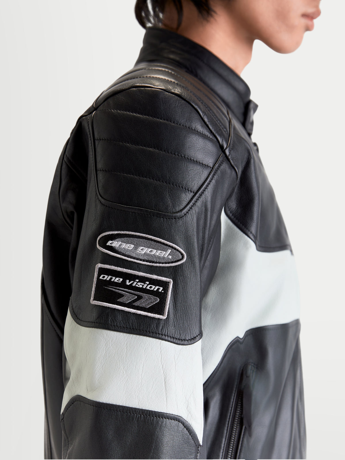 Alpinestars Revern Læderjakke, herre-motorcykeljakke i sort og metalgrå, nærbillede af sideprofil med heritage-inspirerede brandingmærker på ærmet og slidt læderkonstruktion båret af en model