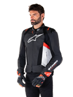 Alpinestars Missile V3 Airflow læderjakke, sort, hvid og rød fluo, racing sport motorcykeljakke, båret af model med matchende handsker, med perforerede læderpaneler, stort hvidt logo på brystet og sorte skulderbeskyttere.
