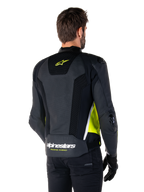 Alpinestars Missile V3 Airflow læderjakke, set bagfra på en mandlig model, sort med fluorescerende gule og hvide detaljer, omfattende perforeret læder og mesh-paneler på ryggen, gult stjerne-logo og hvid 'RACING AHEAD'-tekst, kombineret med sorte handsker og bukser