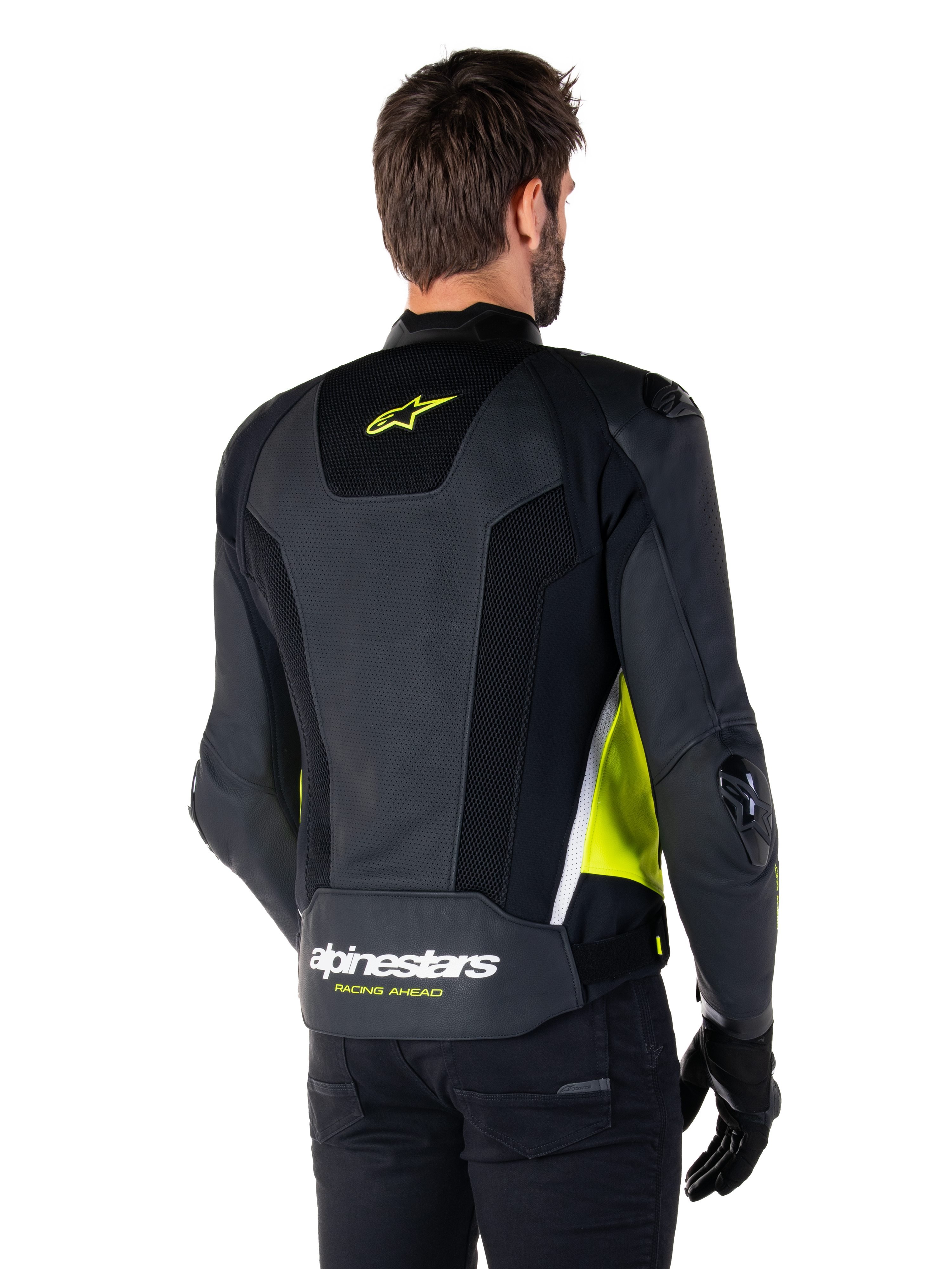 Alpinestars Missile V3 Airflow læderjakke, set bagfra på en mandlig model, sort med fluorescerende gule og hvide detaljer, omfattende perforeret læder og mesh-paneler på ryggen, gult stjerne-logo og hvid 'RACING AHEAD'-tekst, kombineret med sorte handsker og bukser