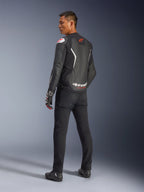 Alpinestars GP Force V2 Leather Jacket, Black and White, rear view showing leather construction with white accents and red logos, worn with black pants and racing gloves, featuring bold Alpinestars branding on the lower back, sport-fit motorcycle gear