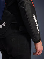 Alpinestars GP Force V2 læderjakke, sort, blå og rød fluo, nærbillede af ærme med hvidt Alpinestars-logo, justerbar taljerem og førsteklasses læderkonstruktion, stylet med sorte motorcykelbukser