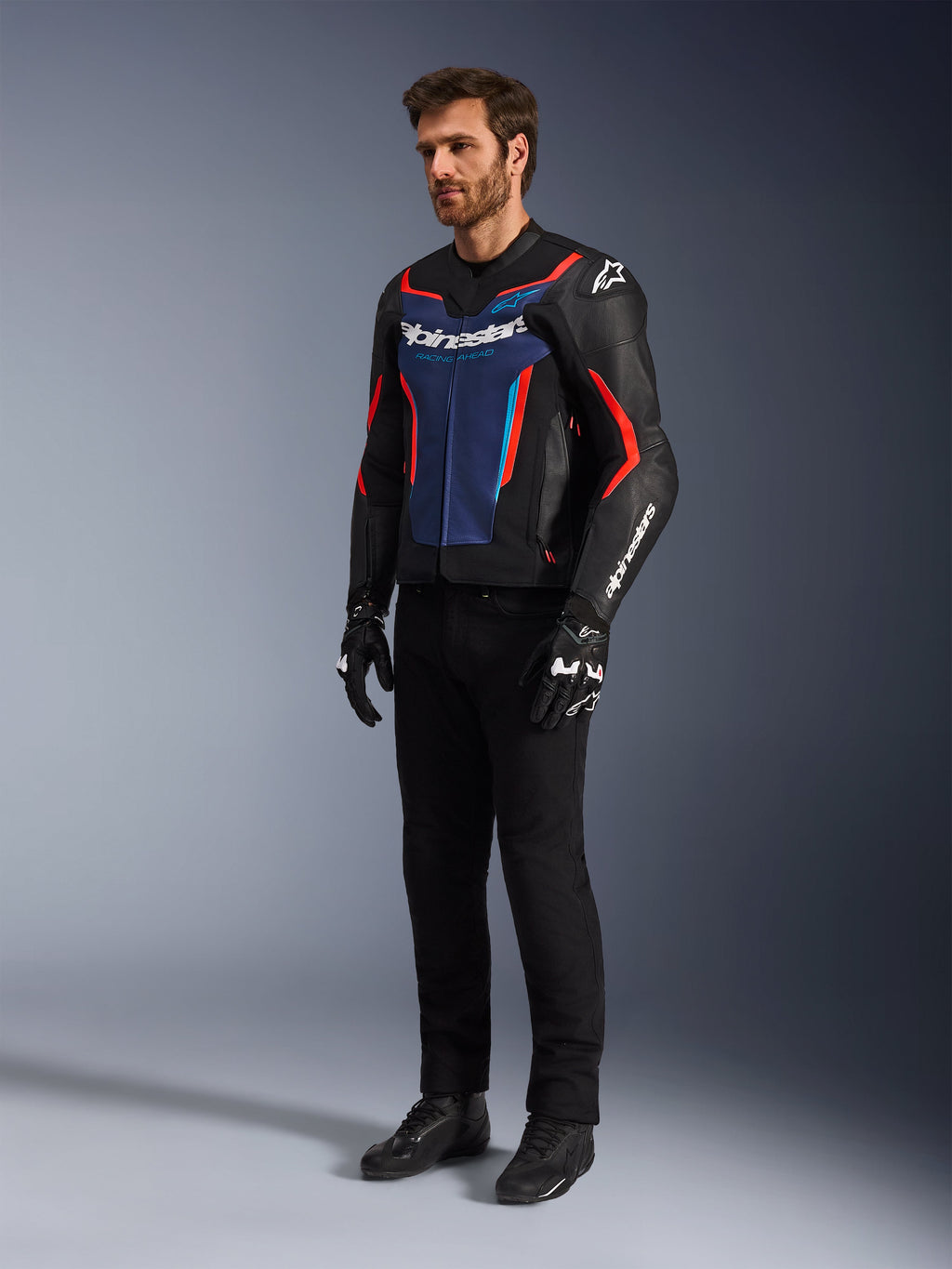 Model iført Alpinestars GP Force V2 læderjakke i Black Blue Red Fluo, kombineret med sorte tekniske kørebukser, sorte handsker og støvler, professionelt motorcykel-racerudstyr til sportskørsel