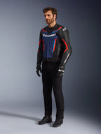 Model iført Alpinestars GP Force V2 læderjakke i Black Blue Red Fluo, kombineret med sorte tekniske kørebukser, sorte handsker og støvler, professionelt motorcykel-racerudstyr til sportskørsel