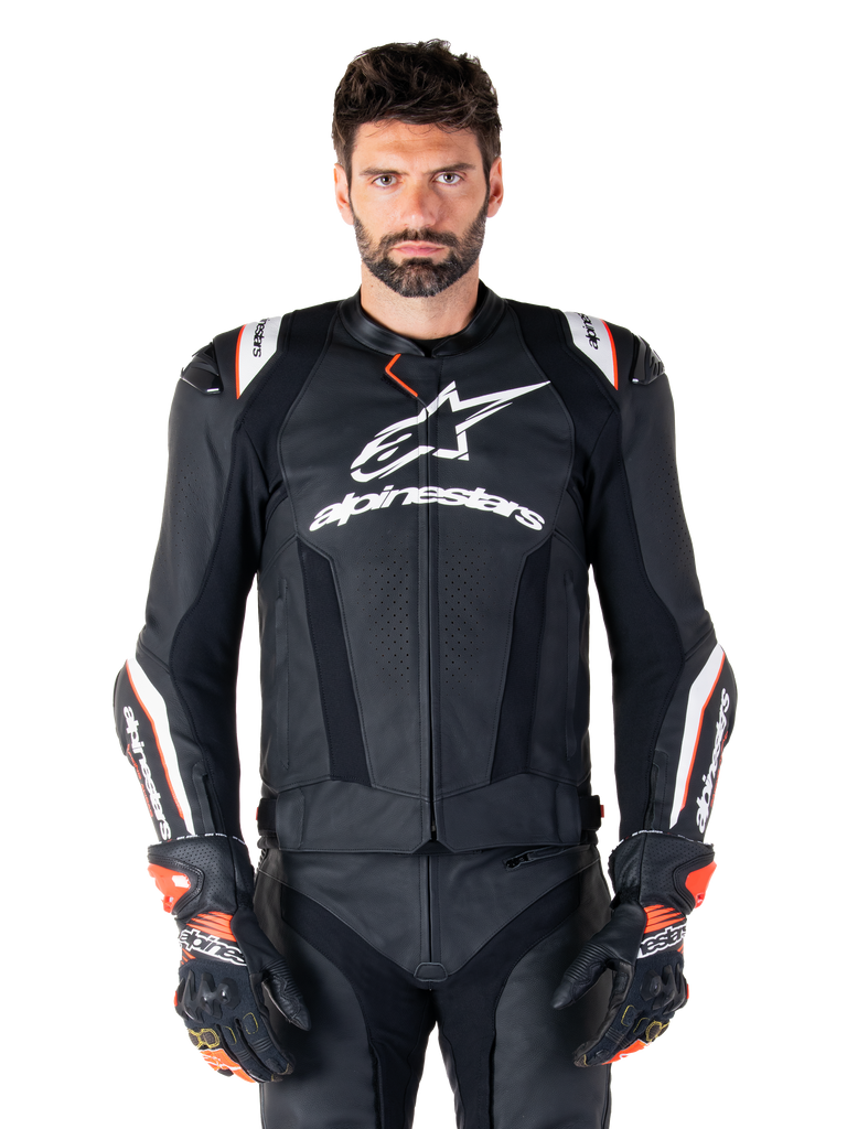 Alpinestars Missile V3 Ignition Leather Jacket, Black with white and red accents, worn by a male model with matching racing gloves and pants, MotoGP-derived sport motorcycle jacket with bold branding