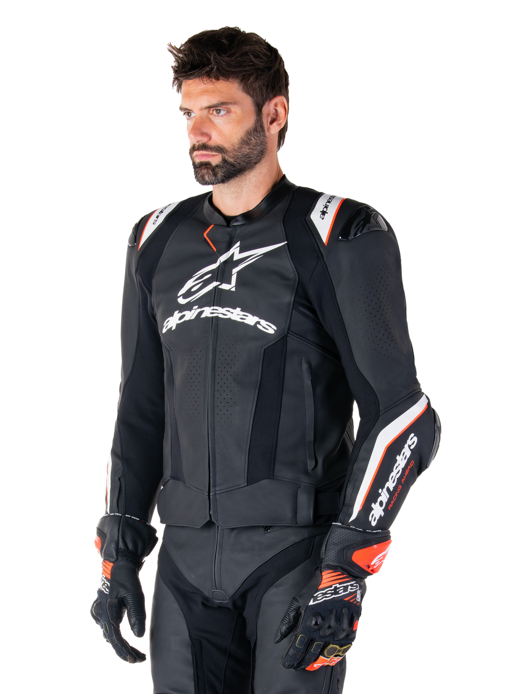 Mandlig model iført Alpinestars Missile V3 Ignition læderjakke, sort med hvide og orange detaljer, fremtrædende hvide logoer, perforerede lædersektioner og beskyttende skulderbeskyttelse, kombineret med racerhandsker for et sport-racing look