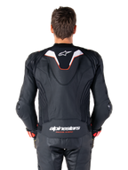 Alpinestars Missile V3 Ignition læderjakke set bagfra, sort læder med hvide og røde detaljer, slank sport aero-hump med hvidt logo, 'alpinestars RACING AHEAD' branding på den nedre ryg, kombineret med matchende sorte læderracerbukser og handsker.