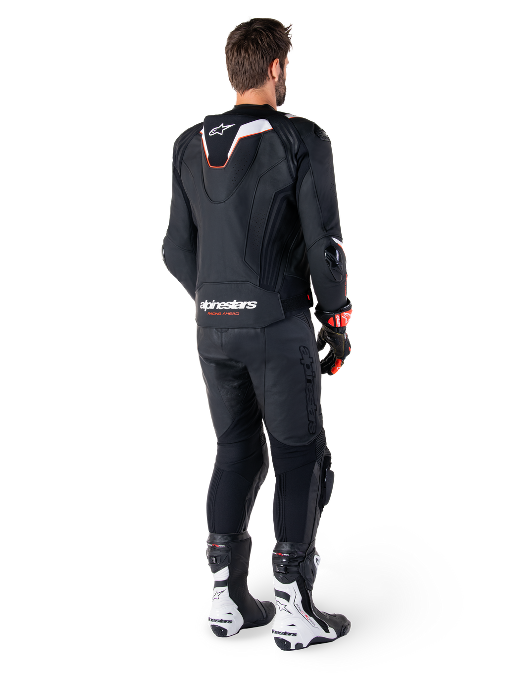 Set bagfra af en kører iført Alpinestars Missile V3 Ignition læderjakke i sort, med en slank sport Aero-hump med hvide og røde detaljer, Alpinestars-branding på den nederste del af ryggen, kombineret med matchende sorte læderbukser og sort-hvide racingstøvler, professionelt sportsudstyr til kørsel