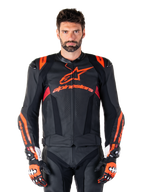 Alpinestars Missile V3 Ignition læderjakke, motorcykelracingjakke, sort og rød fluo, bæres med matchende racinghandsker og læderbukser, med perforeret ventilation og markant Alpinestars-branding, professionelt racingudstyr
