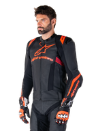 Alpinestars Missile V3 Ignition læderjakke, sort med Red Fluo og mørkerøde detaljer, båret af en mandlig model med matchende racinghandsker og læderbukser, markant Alpinestars-branding, perforerede læderpaneler og eksterne skulderbeskyttere, professionelt motorcykel-racingudstyr