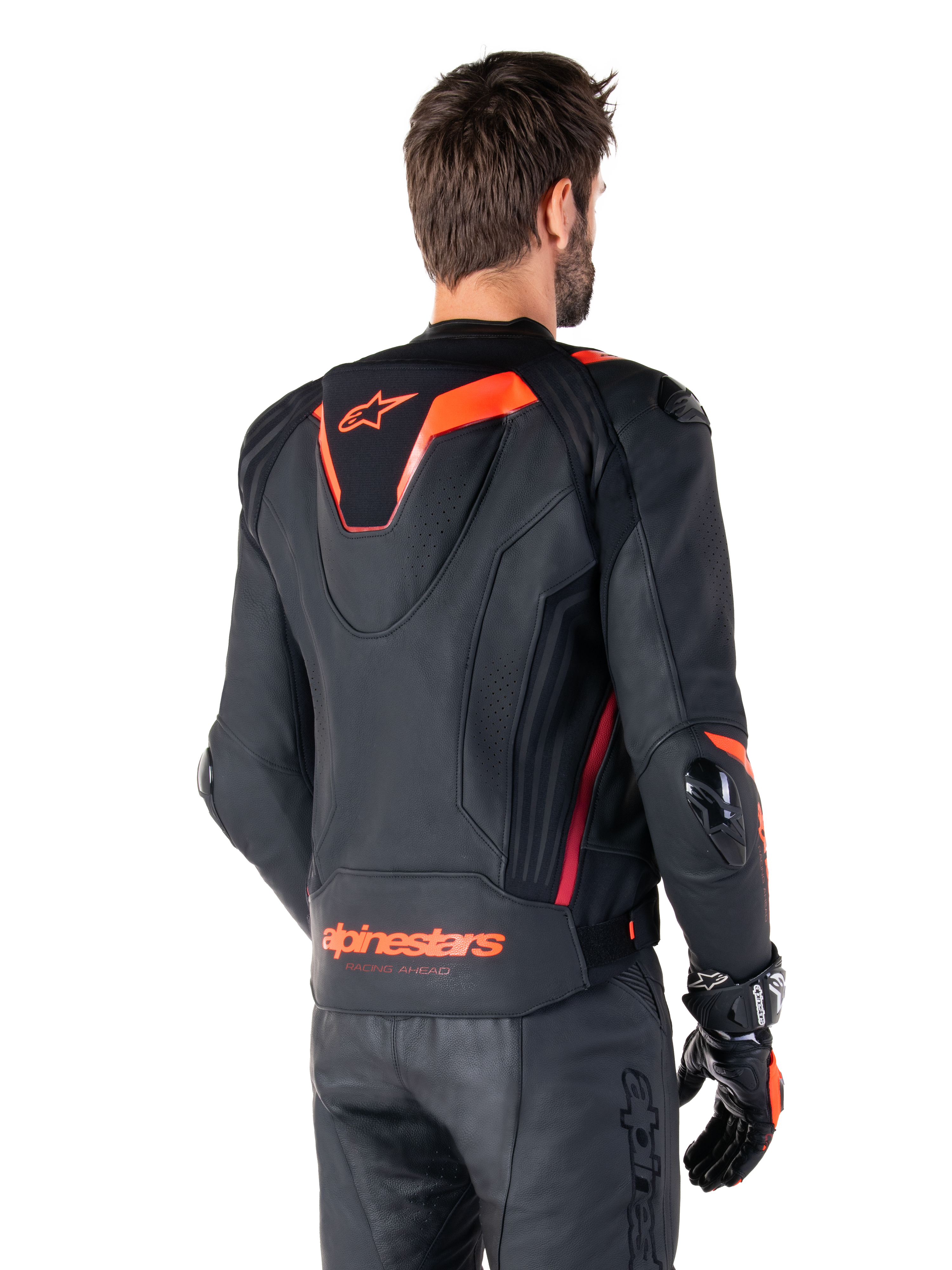 Alpinestars Missile V3 Ignition læderjakke, racing sport jakke til mænd, sort med Red Fluo-detaljer, set bagfra med den slanke aerodynamiske sport-hump og Alpinestars-branding på den nederste del af ryggen, båret med sorte læderbukser og racing-handsker, strømlinet professionelt motorsport-design