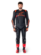 Mandlig model iført Alpinestars Missile V3 Ignition læderjakke i sort, rød fluo og mørkerød, komplet motorcykel-racerudstyr inklusive matchende læderbukser, racerhandsker og støvler, med tydeligt Alpinestars-logo på brystet, frontvendt positur, professionelt sportskøreudstyr