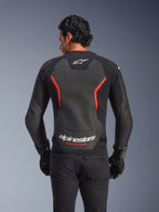 Alpinestars GP Force V2 Air læderjakke, set bagfra, sort og rød fluo, med et stort perforeret rygpanel i læder for ventilation, 'Alpinestars Racing Ahead' branding nederst på ryggen, bæres af en kører med sorte handsker, performance sport motorcykeludstyr