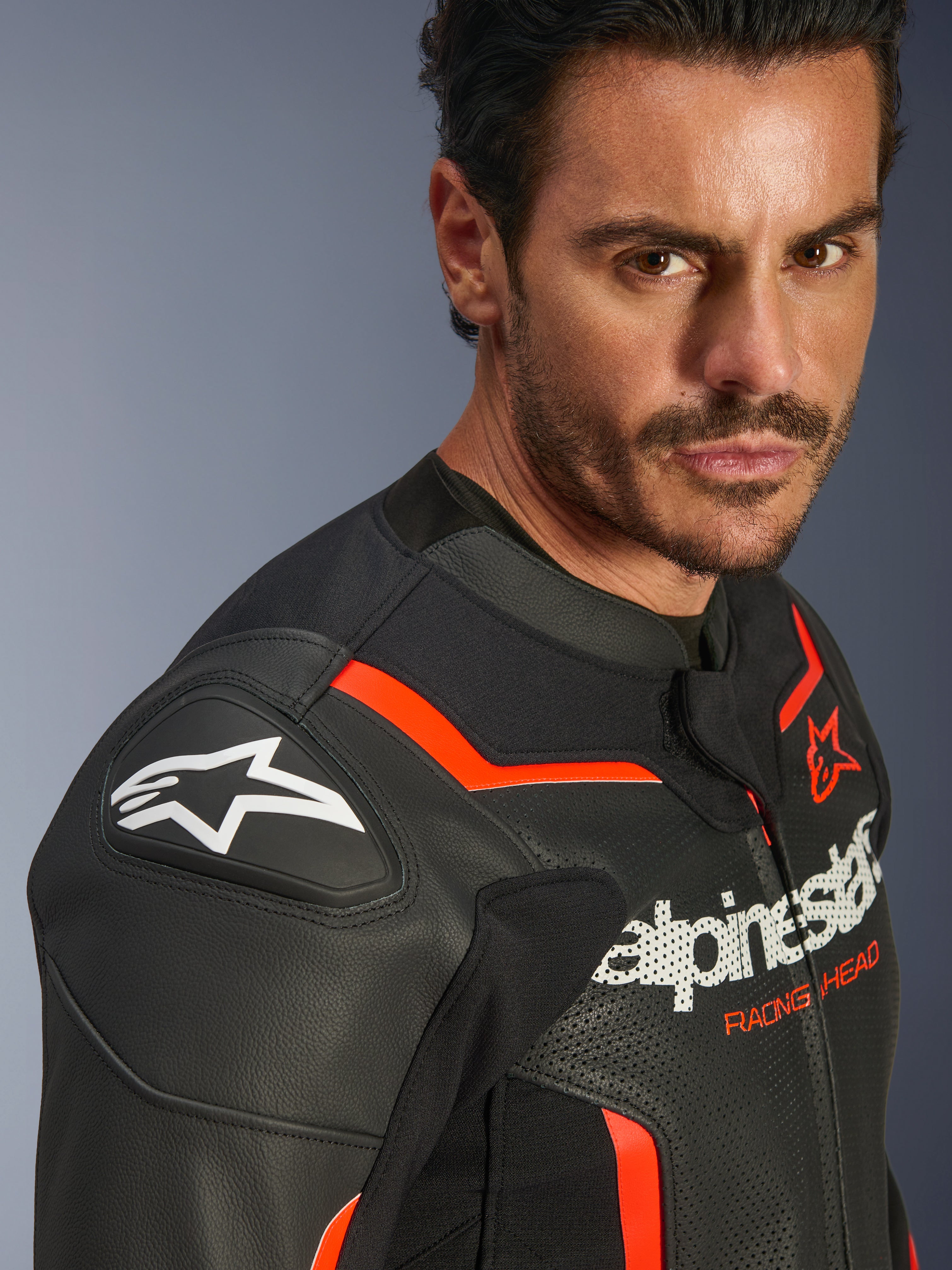 Alpinestars GP Force V2 Airflow læderjakke, sort og rød fluo, båret af en mandlig model, med perforeret læder, GP Lite Evo DFS-skulderbeskyttere og Alpinestars-logo, beskyttelsesudstyr til sportsmotorcykler