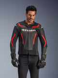 Alpinestars GP Force V2 Air læderjakke, motorcykeljakke til racing, sort og rød fluo, førsteklasses læderkonstruktion med omfattende perforeringer for optimal luftgennemstrømning, båret af en model med sorte handsker og bukser, med markant branding og 'Racing Ahead'-tekst på brystet