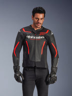 Alpinestars GP Force V2 Air læderjakke, motorcykeljakke til racing, sort og rød fluo, førsteklasses læderkonstruktion med omfattende perforeringer for optimal luftgennemstrømning, båret af en model med sorte handsker og bukser, med markant branding og 'Racing Ahead'-tekst på brystet