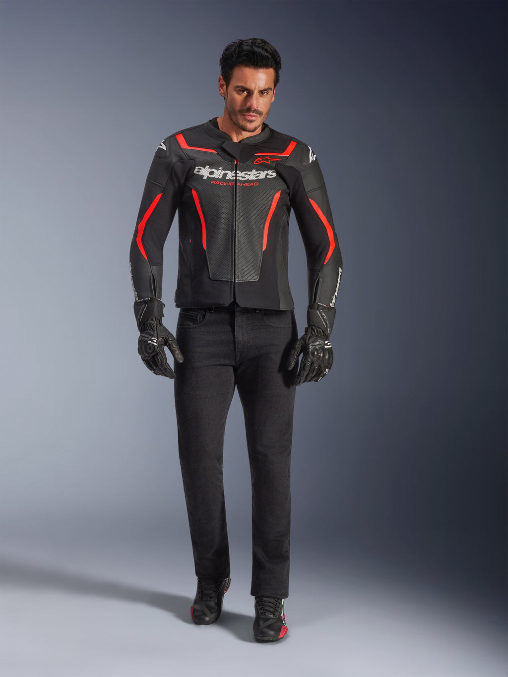 Mandlig kører iført Alpinestars GP Force V2 Air læderjakke, sort og rød fluo, kombineret med sorte kørejeans, handsker og sko, perforeret læderkonstruktion, hvidt logo og røde detaljer, sportsorienteret look
