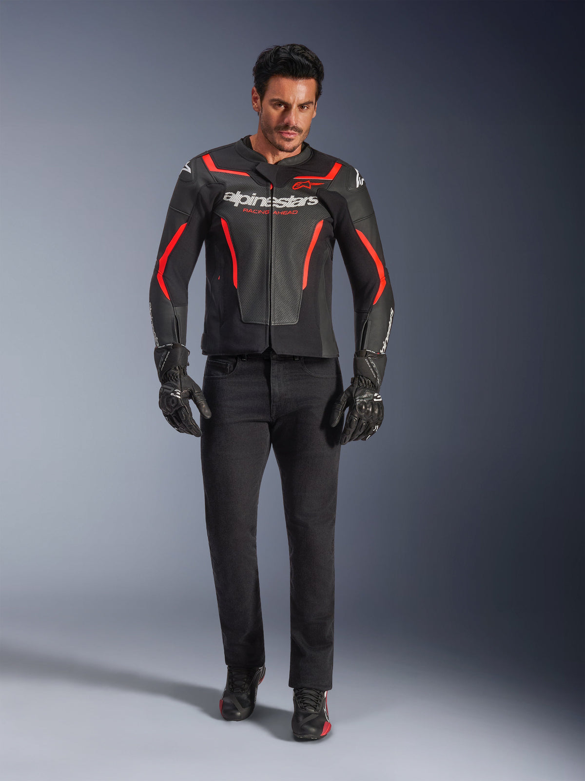 Mandlig kører iført Alpinestars GP Force V2 Air læderjakke, sort og rød fluo, kombineret med sorte kørejeans, handsker og sko, perforeret læderkonstruktion, hvidt logo og røde detaljer, sportsorienteret look