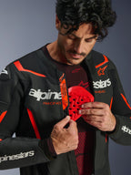 Alpinestars GP Force V2 Air læderjakke i sort og rød fluo, mand der lyner jakken op for at afsløre en rød brystbeskytter, der indsættes, perforeret læder, tydelig hvid branding, Tech-Air Ready-detalje på den indvendige flap