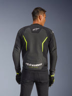 Alpinestars GP Force V2 Air læderjakke, sort og gul fluo, rygvisning af en mandlig kører med omfattende perforerede læderpaneler for luftstrøm, hvid Alpinestars-branding og gul "Racing Ahead"-tekst på den nederste del af ryggen, sportsmotorcykeludstyr til vejbrug.