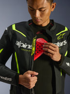 Alpinestars GP Force V2 Air læderjakke, sort og gul fluo, perforeret motorcykeljakke i læder, båret af en kører der demonstrerer brystrummet med et rødt beskyttelsesindlæg, hvid Alpinestars-branding og omfattende perforeringer til luftgennemstrømning.