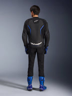 Alpinestars GP Force V2 Airflow læderjakke, Black Metallic Blue, set bagfra med perforerede læderpaneler og hvid branding, båret med blå racingstøvler og sorte bukser, sportsmotorcykel-racerudstyr