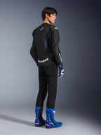 Model set bagfra iført Alpinestars GP Force V2 Airflow læderjakke i Black Metallic Blue, perforerede læderpaneler og hvide logoer, matchende racinghandsker og blå støvler, sportsfokuseret køreudstyr.