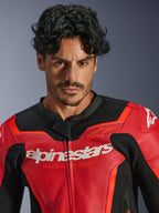 Alpinestars GP Force V2 Air læderjakke, rød og Red Fluo, bæres af en mandlig model, med hvidt Alpinestars- og 'Racing Ahead'-branding på brystet, perforeret læder for luftgennemstrømning, motorcykeludstyr i sportsstil