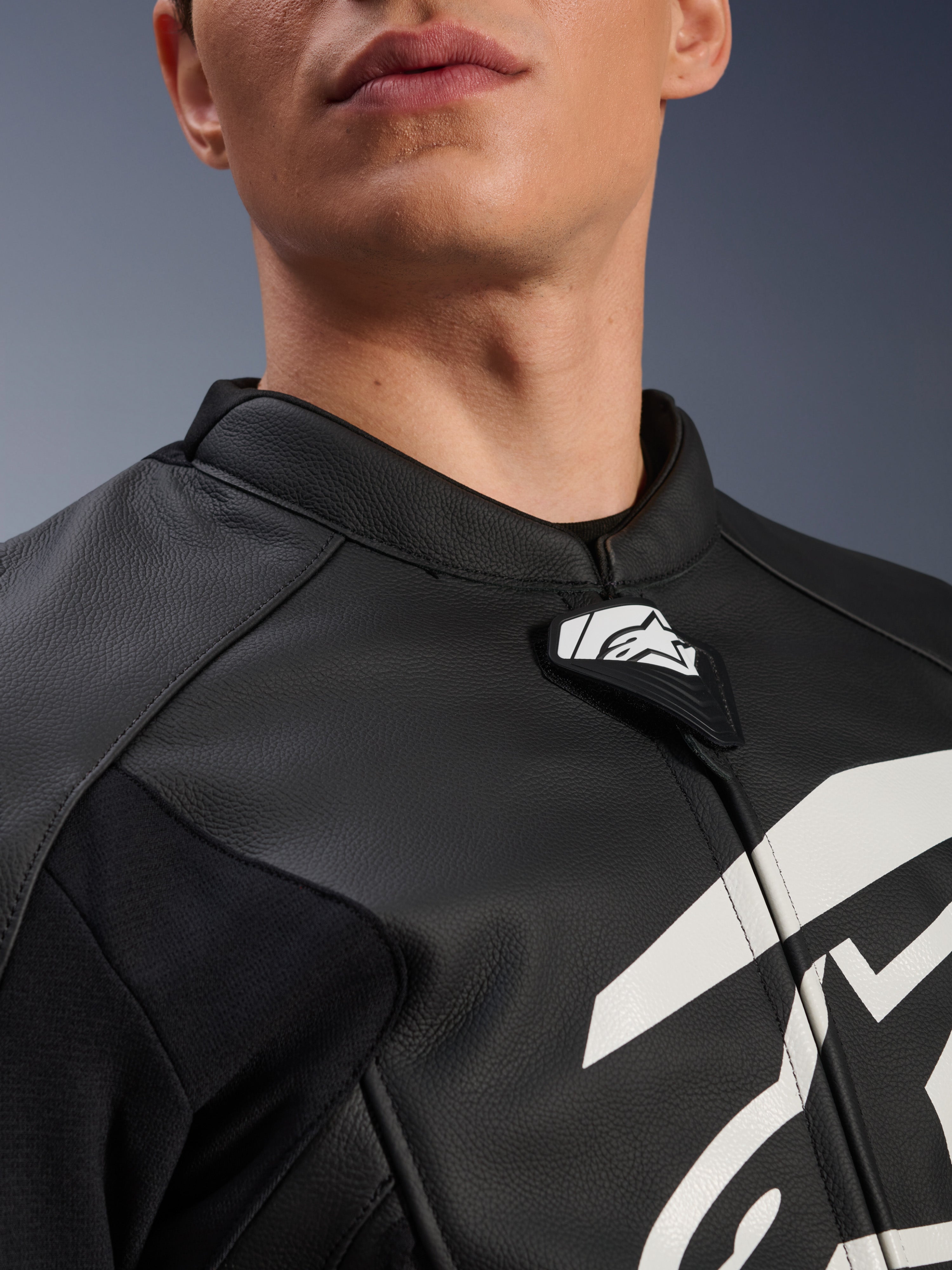 Alpinestars GP Plus V4 Leather Jacket, Sport Motorcycle Jacket, Black and White, close-up of textured leather collar and Alpinestars logo tab, white graphic on chest, race-derived design