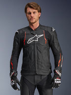 Alpinestars Dusk Airflow læderjakke, sort med rød fluo og hvide detaljer, motorcykel racingjakke i læder, med omfattende perforeringer for ventilation, hvidt logo på brystet og udvendige skulder-sliders, vist på en model med matchende racinghandsker