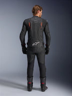 Alpinestars Dusk Airflow læderjakke, sort og rød fluo, bagsidevisning med omfattende perforeringer og stort hvidt logo på lænden, båret med matchende racerudstyr i læder inklusive bukser, støvler og handsker
