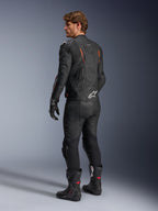 Alpinestars Dusk Airflow læderjakke, sort med Red Fluo-detaljer, set bagfra af en kører i fuldt lædermotorcykeludstyr inklusiv matchende sorte bukser, handsker og racerstøvler, med perforeret læder og hvide Alpinestars-logoer.