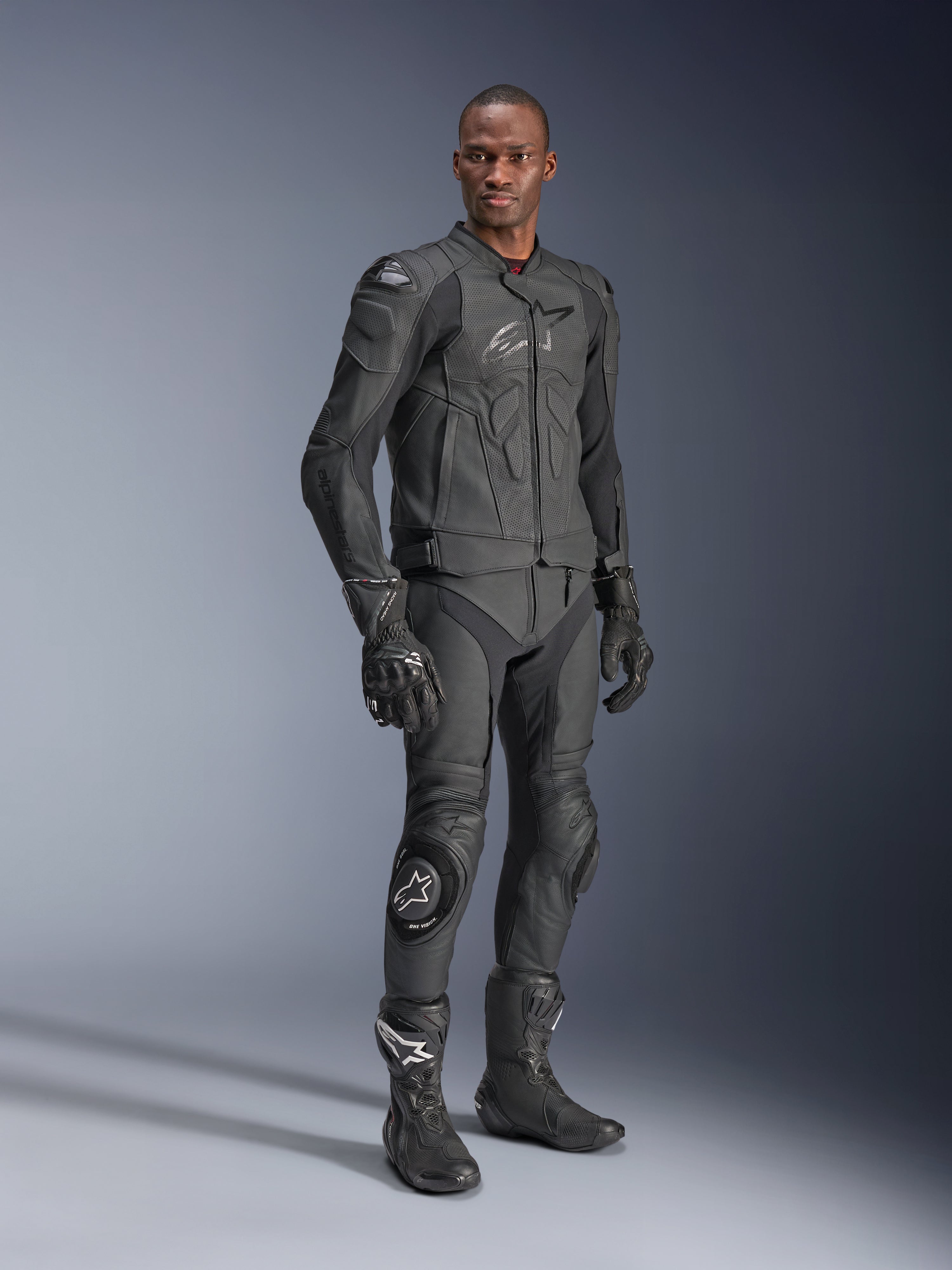 Alpinestars Dusk Airflow læderjakke, sort, båret af en kører i komplet teknisk udstyr inklusive matchende læderbukser, handsker og støvler, med perforerede læderpaneler til ventilation og integreret beskyttelse til sportsmotorcykelkørsel
