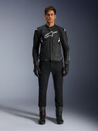 Alpinestars Dusk Airflow læderjakke, sort og hvid, motorcykel læderjakke med perforerede paneler til luftstrøm, hvidt Astars-logo på brystet, båret af en mandlig rytter med sorte bukser, handsker og kørestøvler, professionelt studiebillede af sportsmotorcykeludstyr.