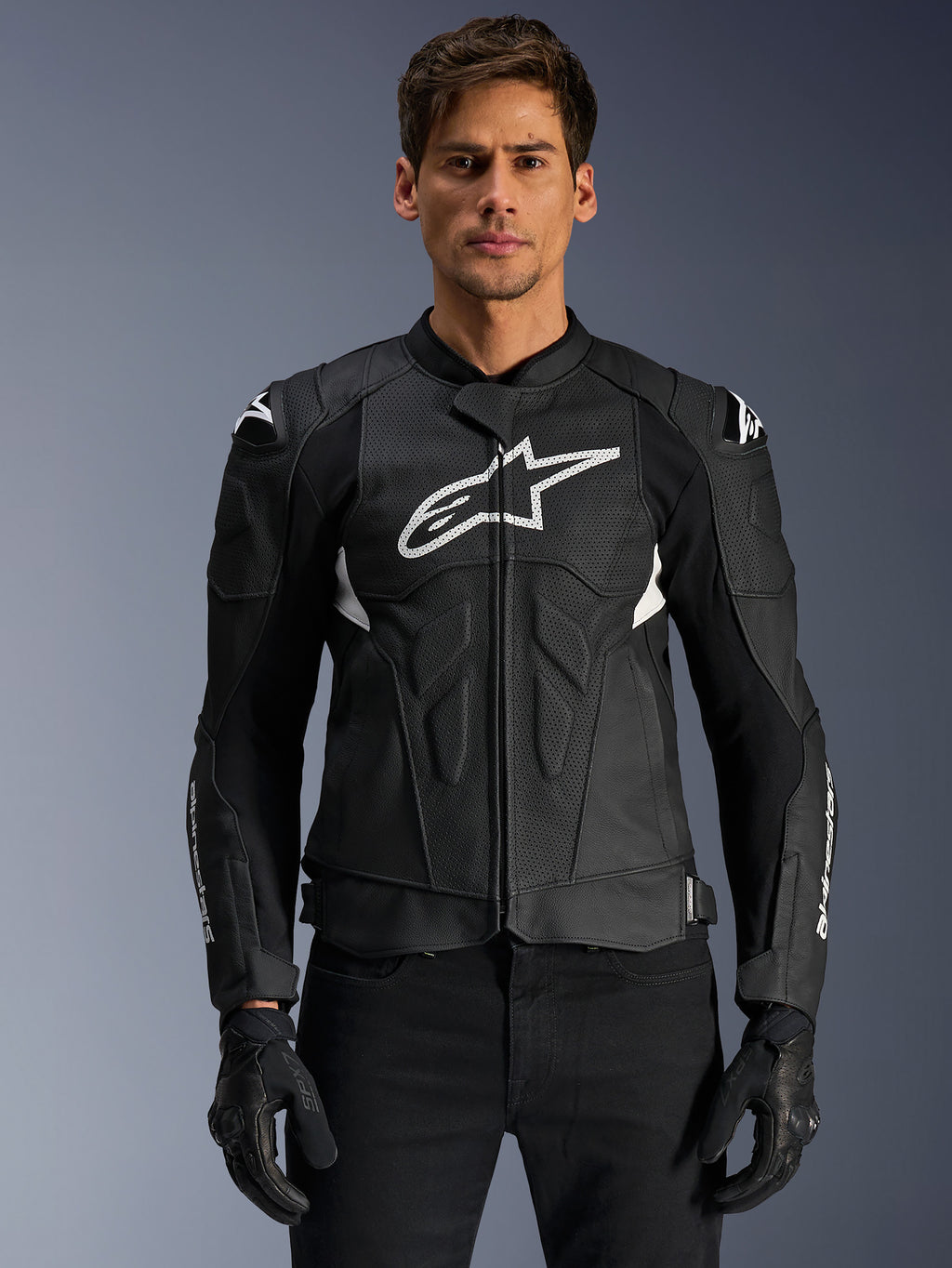 Alpinestars Dusk Airflow læderjakke, sort og hvid, motorcykeljakke i læder båret af en model, med perforerede læderpaneler til ventilation, et stort hvidt logo på brystet og udvendige skulder-sliders.