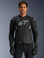 Alpinestars Dusk Airflow læderjakke, sort og hvid, motorcykeljakke i læder båret af en model, med perforerede læderpaneler til ventilation, et stort hvidt logo på brystet og udvendige skulder-sliders.